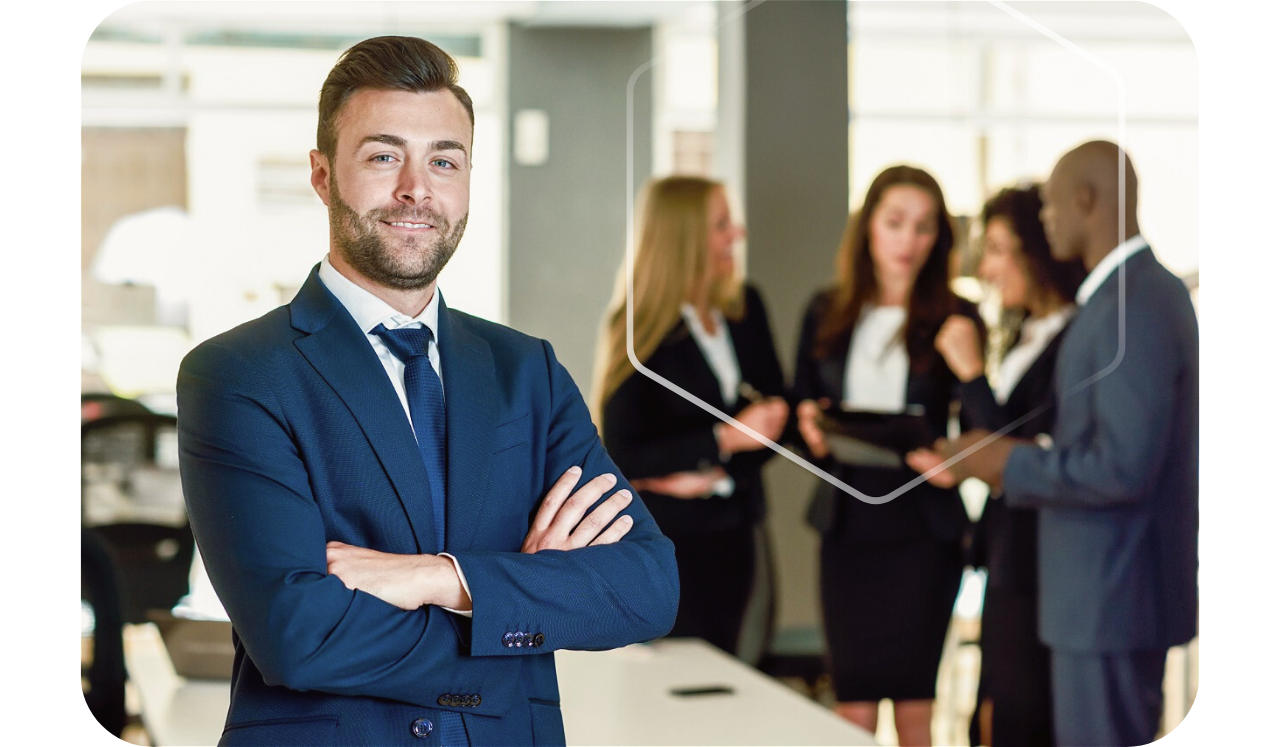 Foto de um homem empresário cruzando os braços e sorrindo na frente e um grupo de funcionários conversando atrás dele, envolvidos em um hexágono