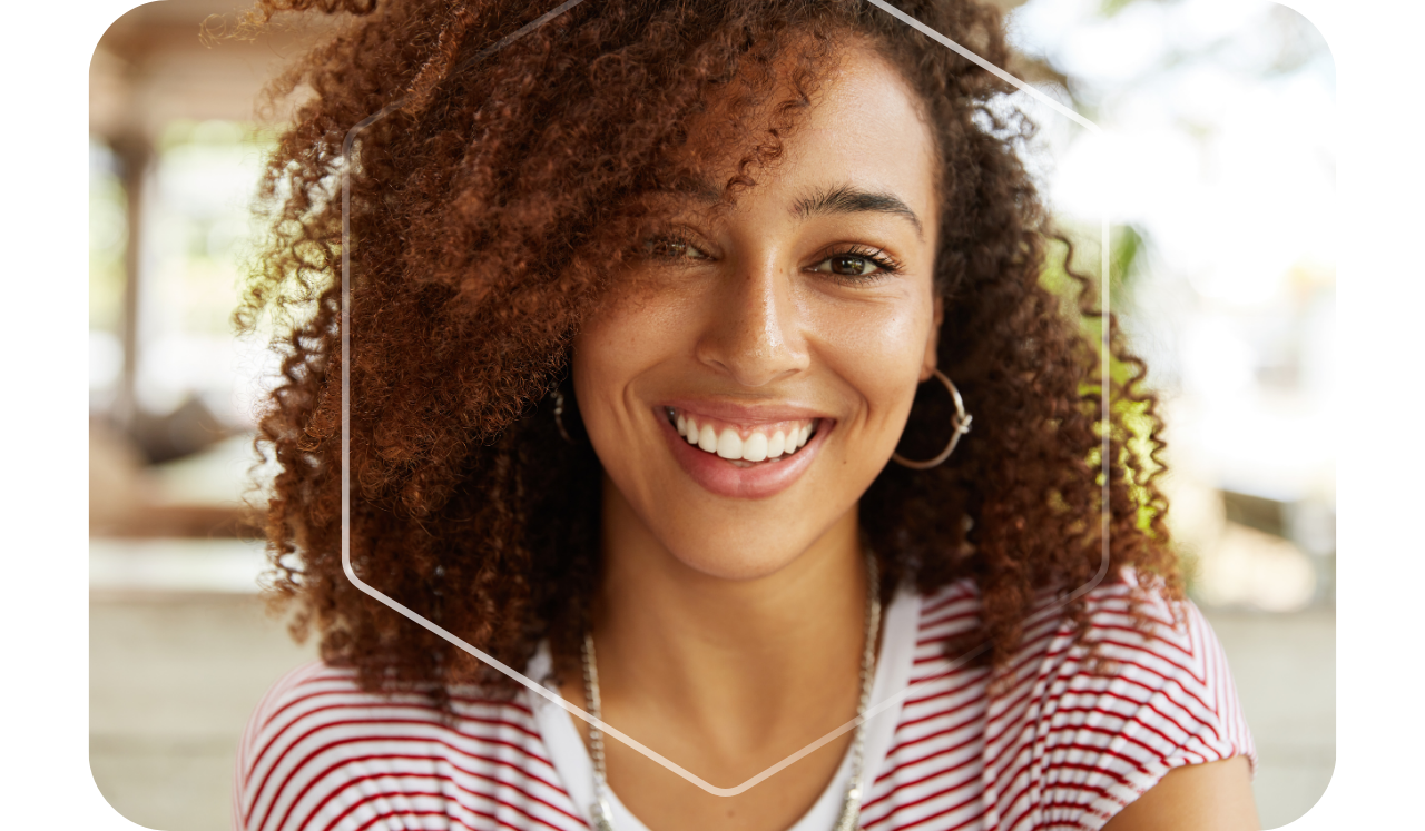 Foto de uma mulher sorrindo, com o foco no sorriso dela, fundo desfocado e um hexágono em sua volta