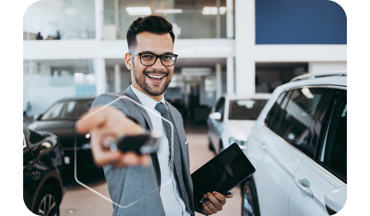 Foto com pessoa estendendo a mão segurando uma chave de carro em uma loja de carros, simbolizando o consórcio de carros