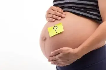 Barriga de uma gestante com um bilhete adesivo amarelo marcado com um sinal de interrogação