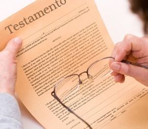Mãos segurando um documento intitulado Testamento e um par de óculos de leitura