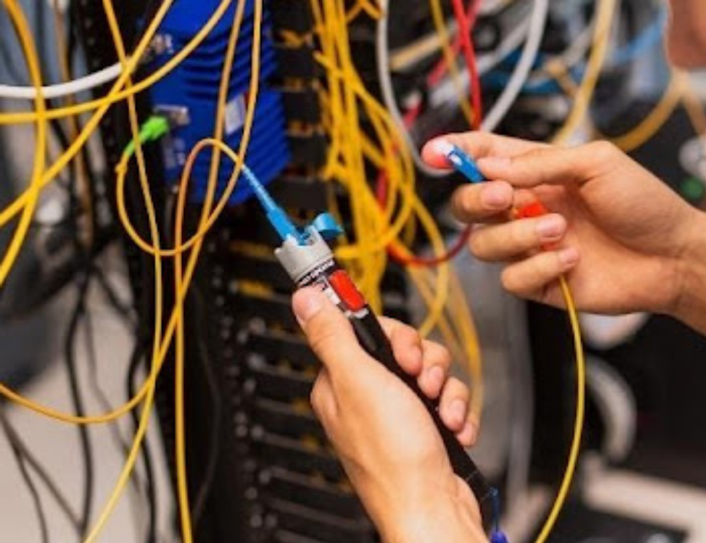Técnico utilizando ferramenta de teste em painel com cabeamento estruturado, ilustrando a importância da organização e verificação de conexões para evitar queda de tensão em instalações elétricas industriais e sistemas de automação.