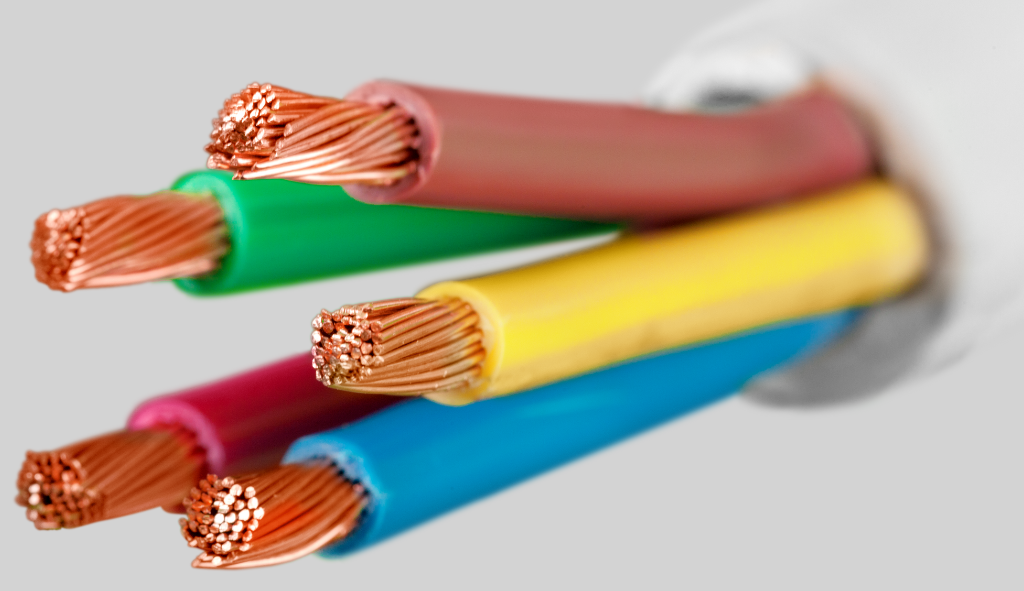 Carretéis de cabos nus de alumínio e cobre lado a lado, representando a comparação entre os dois materiais condutores utilizados em instalações elétricas. Imagem ilustrativa para entender as vantagens, aplicações e diferenças de desempenho entre cabos de cobre e alumínio.