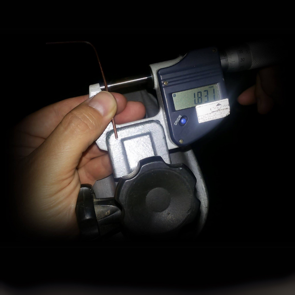 Micrômetro digital medindo o diâmetro de um fio de cobre com precisão de 1,837 mm, ilustrando a etapa fundamental para calcular a capacidade de corrente elétrica conforme a bitola do cabo.