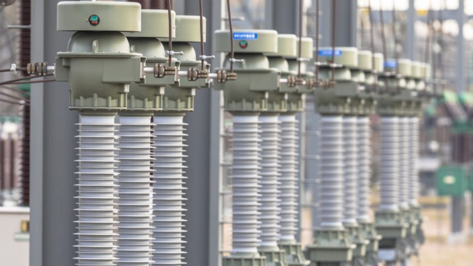 Equipamentos de subestação com isoladores, ilustrando a diferença entre sistemas monofásico, bifásico e trifásico na distribuição elétrica.