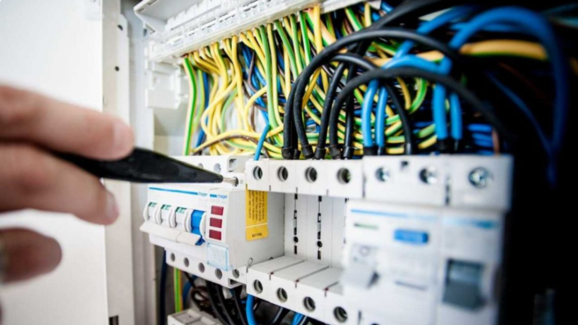 Técnico manuseando quadro elétrico com fios coloridos organizados, destacando a importância das cores dos cabos na identificação e segurança das instalações.