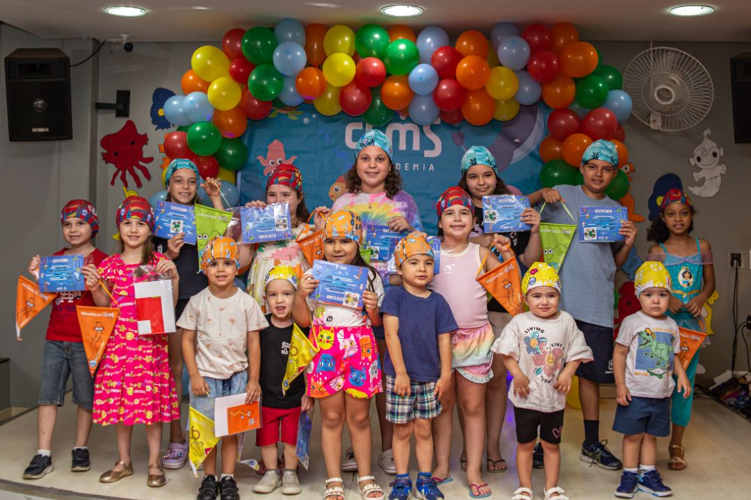 Alunos de natação com touca, flâmula e certificado de troca de nível da Metodologia Gustavo Borges